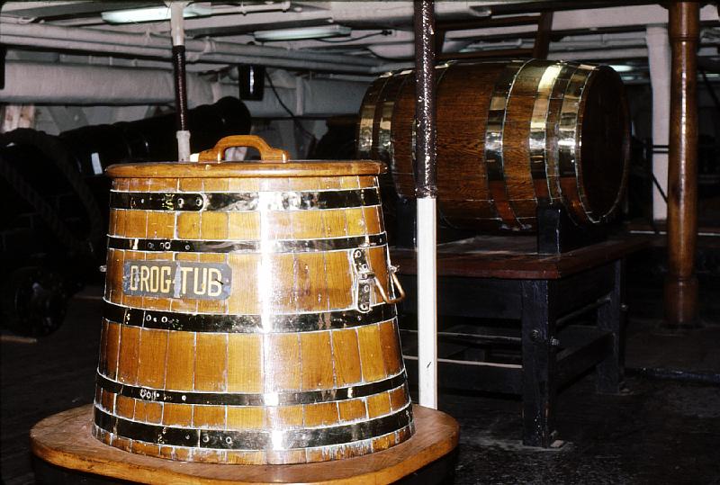 24-grog_tub_and _scuttlebut Grog was rum with water added. The mixture, unlike pure rum, would spoil, preventing the crew from hoarding rum to get drunk on.  The barrel behind it is the butt of water, which was dispensed with a wooden drinking scuttle.  To this day, 